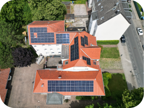 Draufsicht auf Solaranlagen, die sich auf einem roten Dach eines verwinkelten Hauses befinden