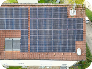 Draufsicht auf Solaranlage auf einem roten Dach mit Dachfenstern