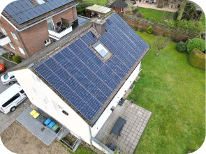 Weißes Haus mit Garten, bei dem eine Dachhälfte mit Solaranlagen bedeckt ist