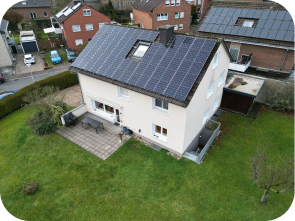 Draufsicht auf weißes Haus mit Garten, bei dem eine Dachhälfte mit Solaranlagen bedeckt ist