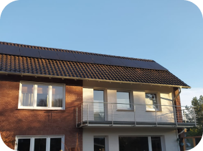 Haus, das von der Sonne angestrahlt wird, mit Solaranlagen auf dem Dach