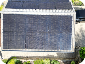 Weiße Garage vor der ein Auto parkt, mit einer Solaranlage auf dem Dach aus der Vogelperspektive