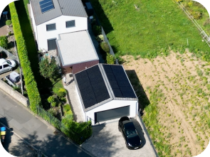 Draufsicht auf Weiße Garage vor der ein Auto parkt, mit einer Solaranlage auf dem Dach